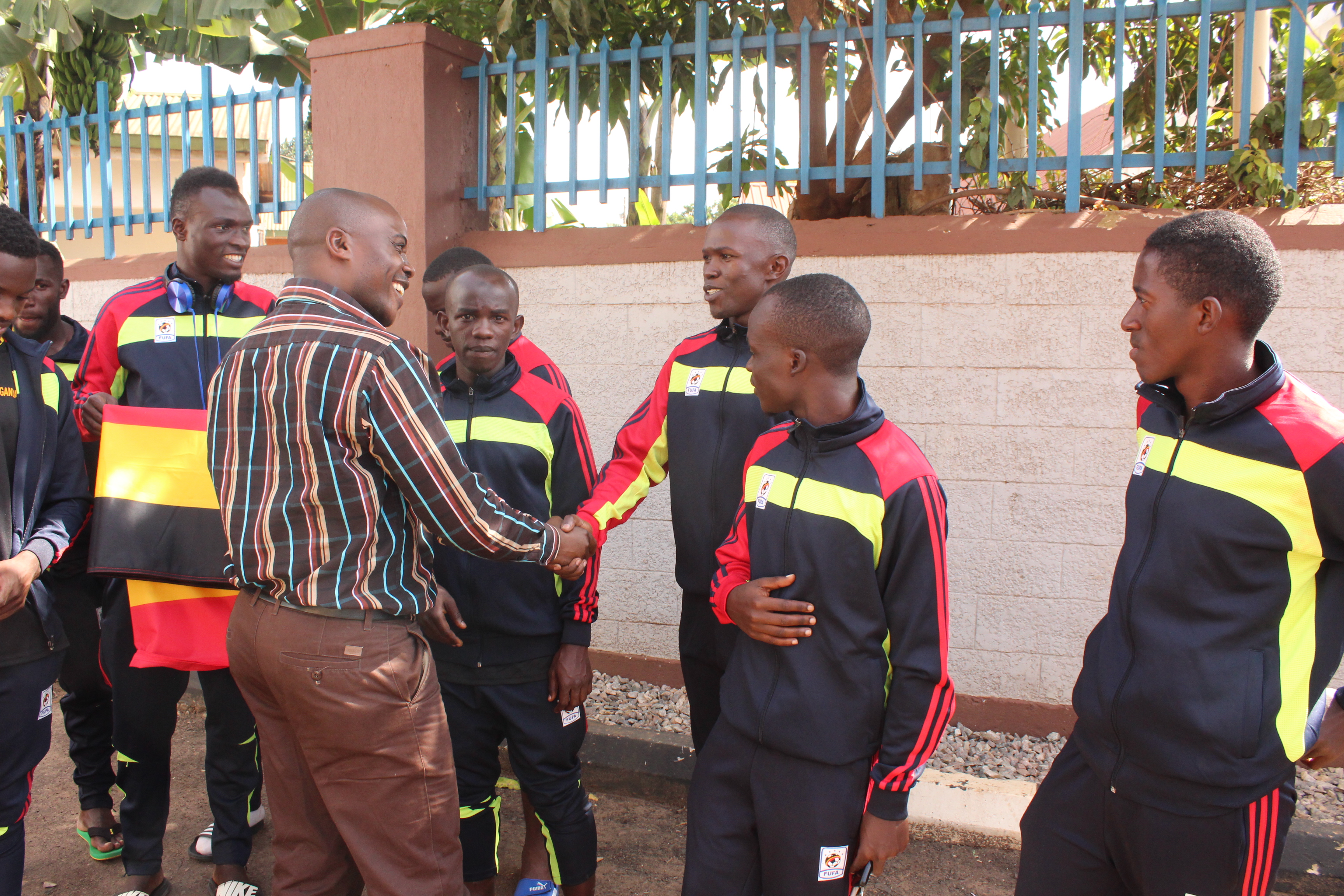 Mr. Samuel Mpiima greets each of the Sand Cranes players who traveled with the team moments after he flagged off the team