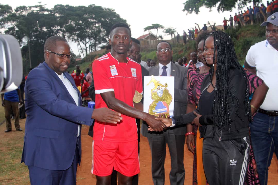 Bukedi's Ronald Musana recieves man of the match accolade and cash prize from Princess Ssangalyambogo as FUFA Drum Rogers Byamukama the FUFA Drum organising Committee chairman looks on